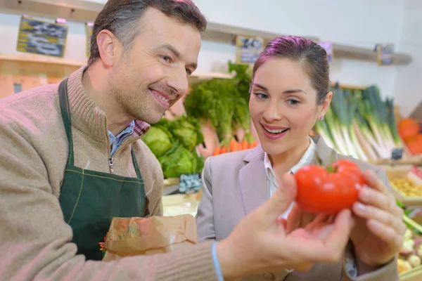 Mujer sonriente eligiendo diferentes frutas en la exhibición de la tienda de alimentos de granja —  Fotos de Stock