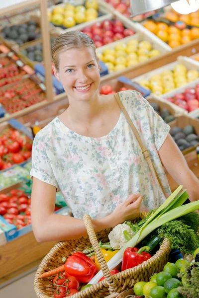 Dame im Supermarkt hält Gemüsekorb — Stockfoto