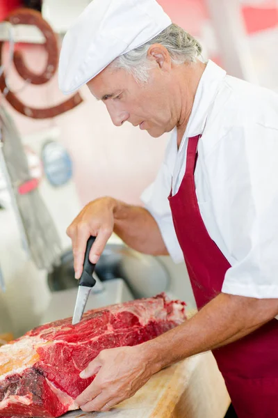 Мясник режет мясо — стоковое фото