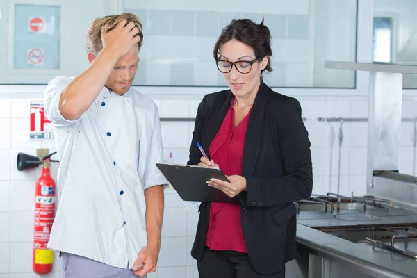 Middle aged supervising telling off trainee in the kitchen — Stock Photo, Image
