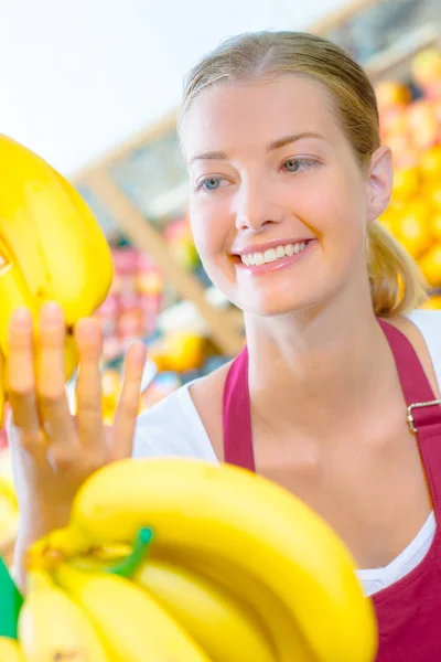 Assistente de loja segurando bananas — Fotografia de Stock