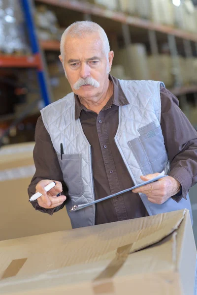 Старший работник проверяет картон на складе для доставки — стоковое фото