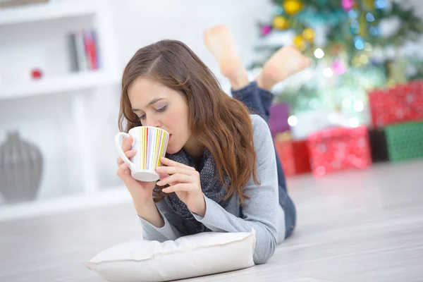 Donna con tazza di tè sdraiata sul pavimento a casa — Foto Stock