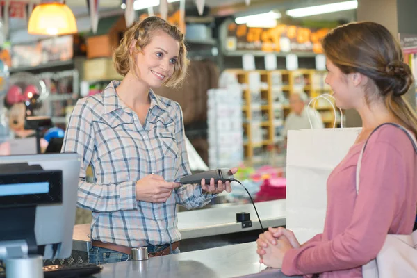 Mladá žena platí kreditní kartou v obchodě — Stock fotografie