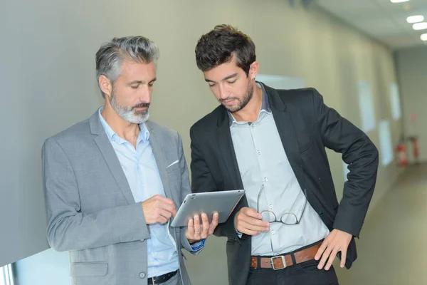 Partner commerciali che lavorano in corridoio con tablet elettronico — Foto Stock