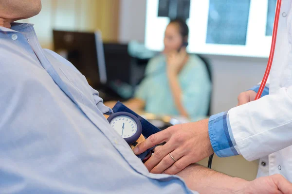 Médico tomando la presión arterial del paciente — Foto de Stock