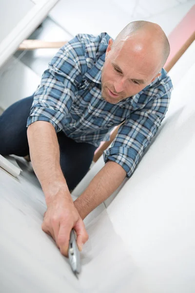 Handyman fitting carpet while installation with cutter — Stock Photo, Image