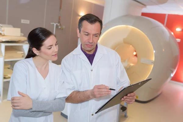 Врач стоя руки скрещенные пациентом лежа на МРТ — стоковое фото