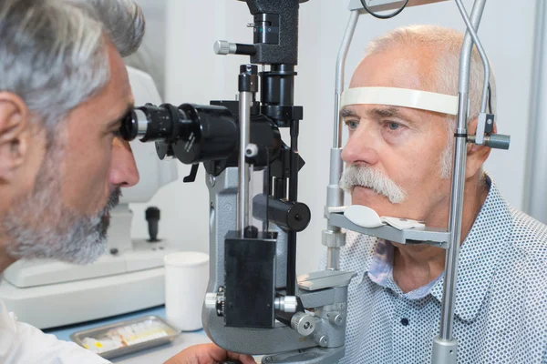 Sênior fazendo um exame oftalmológico em ópticos — Fotografia de Stock