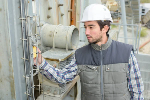 Travailleur industriel regardant l'étiquette sur l'équipement extérieur — Photo