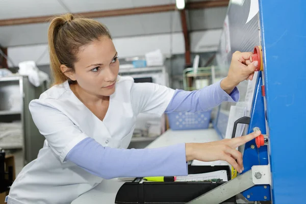 Unga kvinnliga ingenjör som arbetar på maskinen i fabriken — Stockfoto