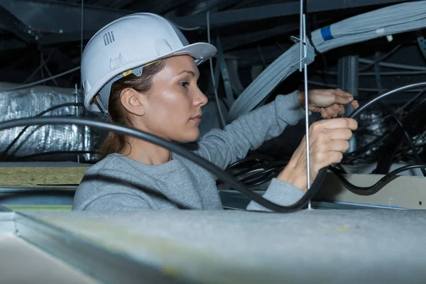 Electrician tending to wiring in roof space — Stock Photo, Image