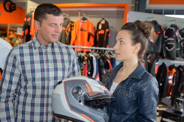 Vendedor feminino mostrando capacete ao cliente na loja de moto — Fotografia de Stock