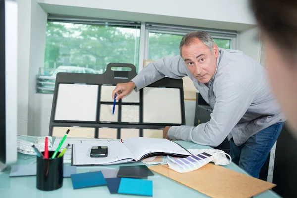 Colleagues looking at sticky notes on board in the office — Stock Photo, Image