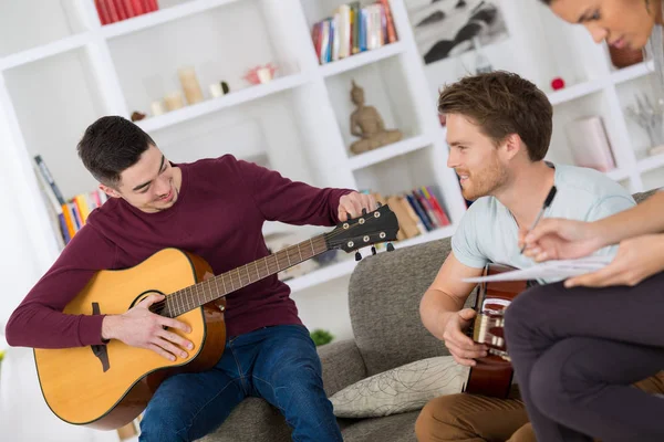 Szczęśliwi przyjaciele grający na gitarze i słuchający muzyki w domu — Zdjęcie stockowe