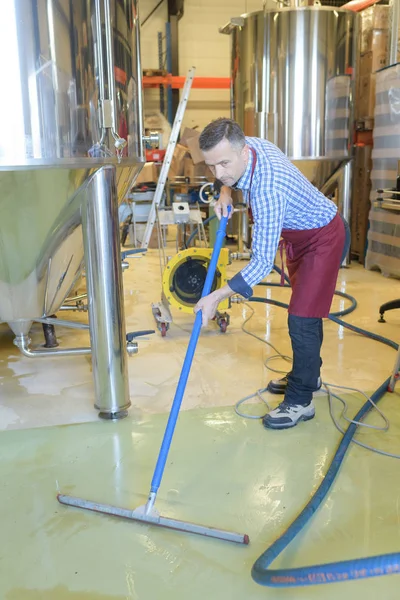wine factory worker cleaning floor