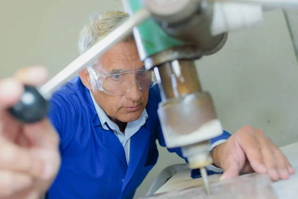 Taladro de carpintero senior en tablón en su taller — Foto de Stock