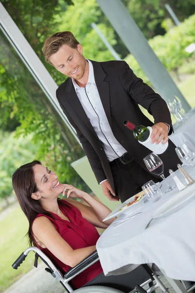 Mulher sorridente em uma cadeira de rodas sendo servida em um restaurante — Fotografia de Stock