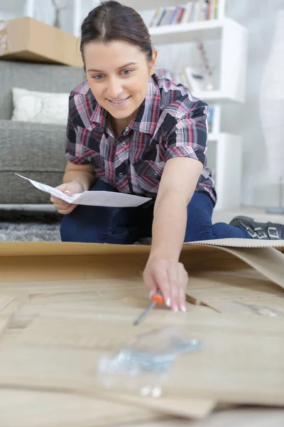 Handywoman την εγκατάσταση ξύλινο πάτωμα στο σαλόνι — Φωτογραφία Αρχείου