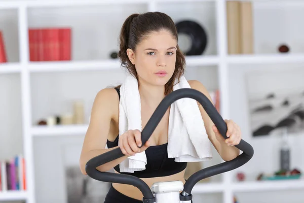 Young sporty woman training on exercise bike — Stock Photo, Image