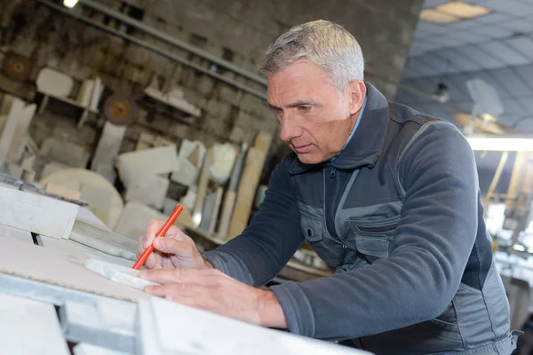 Falegname anziano che segna una misurazione su una tavola di legno — Foto Stock