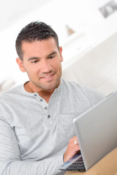 Man van middelbare leeftijd op laptopcomputer van thuiswerken — Stockfoto