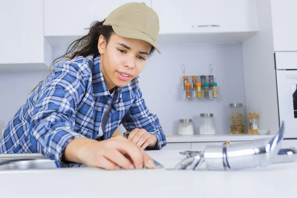 Unga kvinnliga rörmokare arbetar på diskbänken — Stockfoto