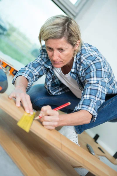 Ženské carpenter měření vhodné dřevěné desce v dílně — Stock fotografie