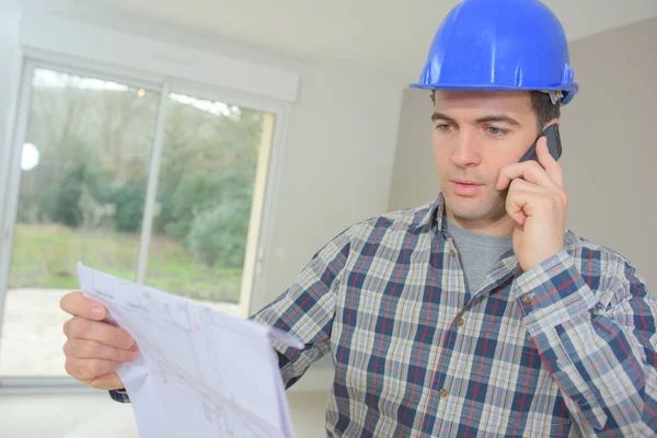 Uomo con cianografie e che parla al telefono — Foto Stock