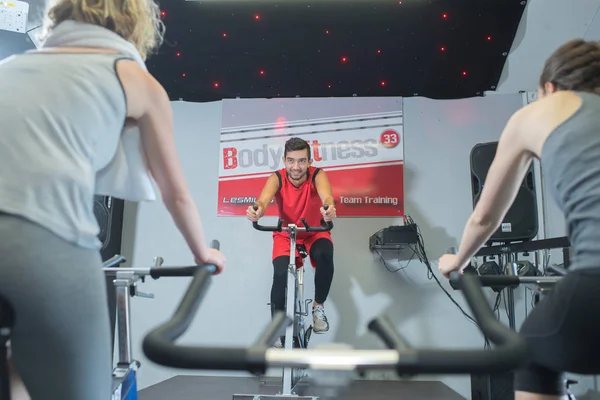 Gente feliz haciendo ciclismo indoor en un gimnasio —  Fotos de Stock