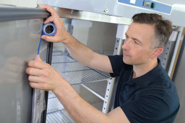 Reifer männlicher Techniker misst Kühlschrank — Stockfoto