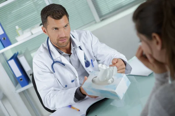 Doctor consoling upset woman and passing her a tissue — Stock Photo, Image