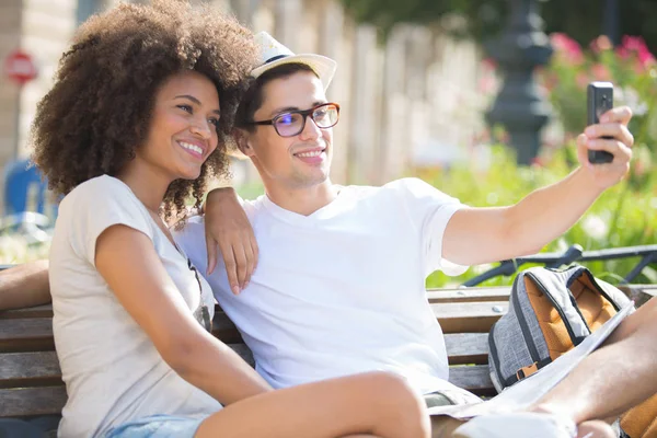 Young couple taking selfie sitting on a bench — Stock Photo, Image
