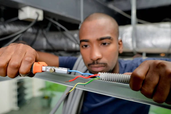 Eletricista usando cortadores para cortar fio — Fotografia de Stock