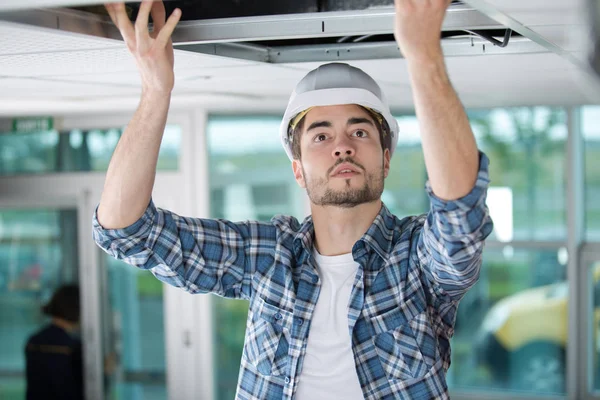 Elektricien werkt door een open plafondluik — Stockfoto