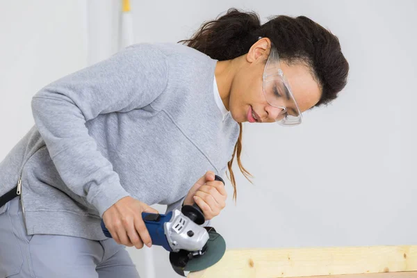 Жінка шліфує дерев'яний стіл електричним шліфувальником — стокове фото