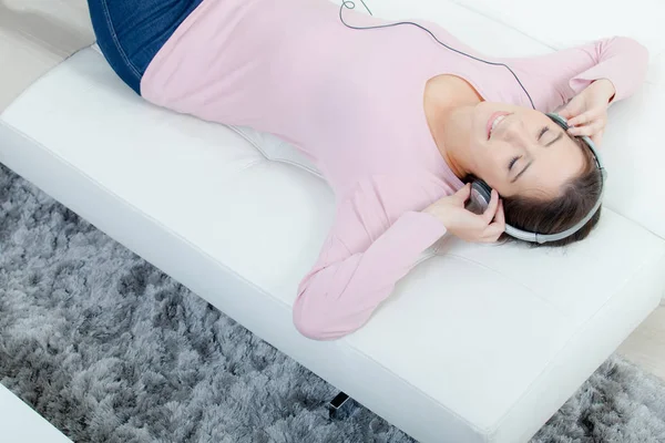 Kadın onun kanepede müzik dinlemek — Stok fotoğraf
