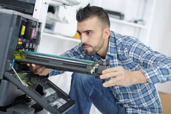 Genç erkek teknisyen dijital fotokopi makinesini tamir ediyor. — Stok fotoğraf