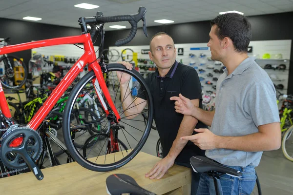 Hombre comprueba bicicleta antes de comprar en la tienda de deportes — Foto de Stock