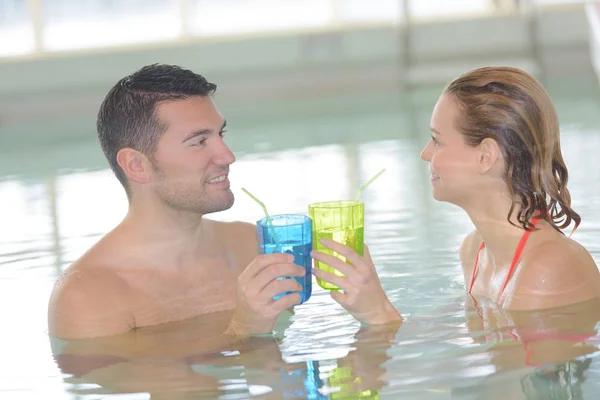 放松的情侣在度假村游泳池喝鸡尾酒 — 图库照片