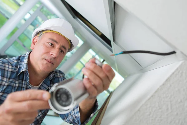 technician worker installing video surveillance camera on wall