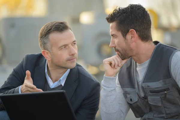 Geschikt man en workman laptop buiten kijken — Stockfoto