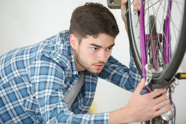 Hombre rueda de fijación de la bicicleta en casa — Foto de Stock