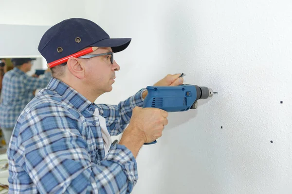 Hombre perforando la pared con taladro de impacto — Foto de Stock