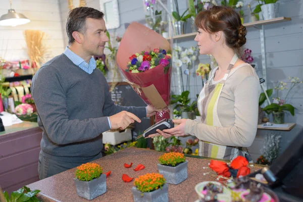Флорист держит карточку платежной машины к клиенту — стоковое фото