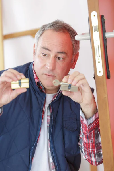 Maturo tecnico fissaggio serratura in porta in casa dei clienti — Foto Stock