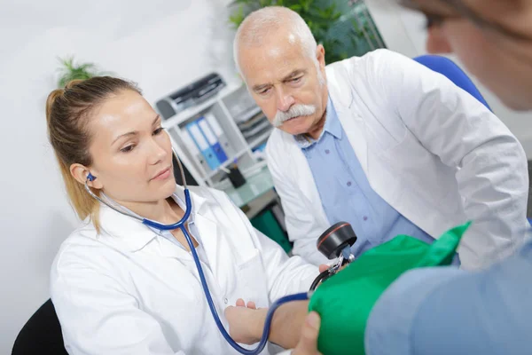 Médicos revisando paciente y médico —  Fotos de Stock