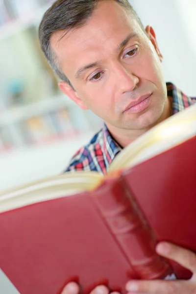 Homme lisant un livre rouge — Photo