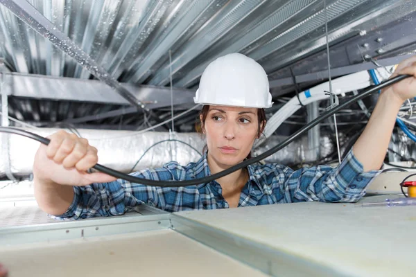 建物の天井内の配線女性電気技師 — ストック写真