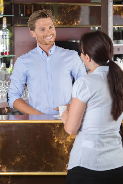 Mężczyzna barista flirtuje z kobieta klienta w kasie — Zdjęcie stockowe